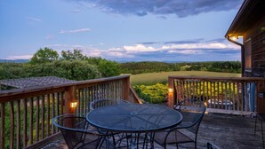 A wooden deck with a round table and chairs, overlooking a grassy landscape and trees. - Ridgeview Retreat (Staunton)