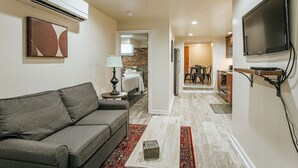 Un salon moderne avec un canapé gris, une table basse et un téléviseur fixé au mur.