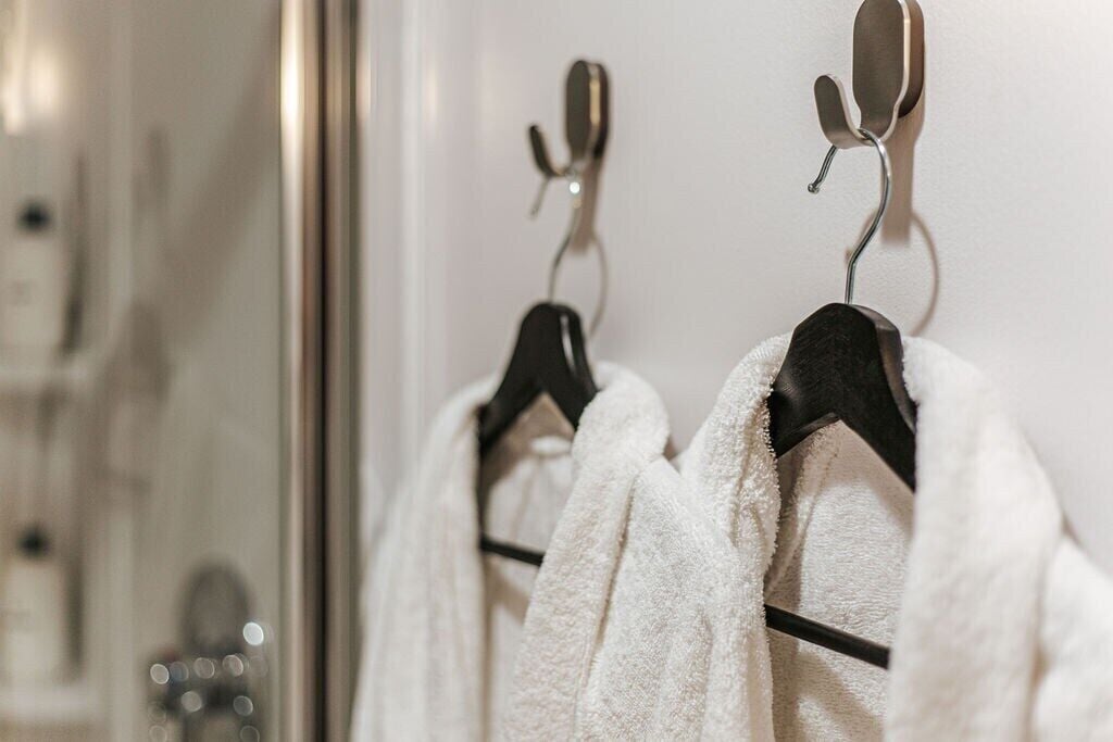 A bathroom with two white towels hanging on black hooks.