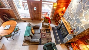 A cozy cabin interior with a stone fireplace, a dining area, and a sofa.