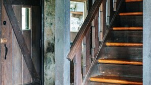 Una escalera de madera con barandilla y una puerta con picaporte de metal.