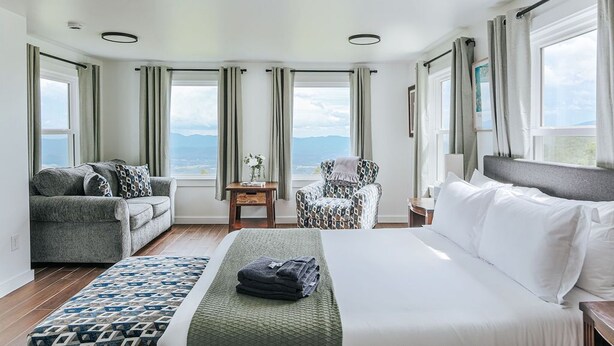 Habitación de hotel con cama, sofá, sillón y vistas a las montañas.