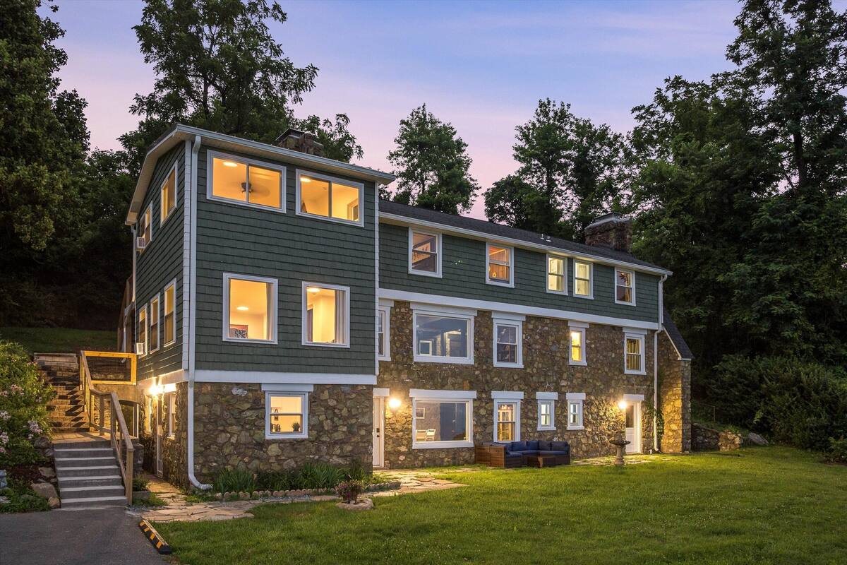 A multi-story house with a stone facade, a front porch, and a well-maintained lawn.