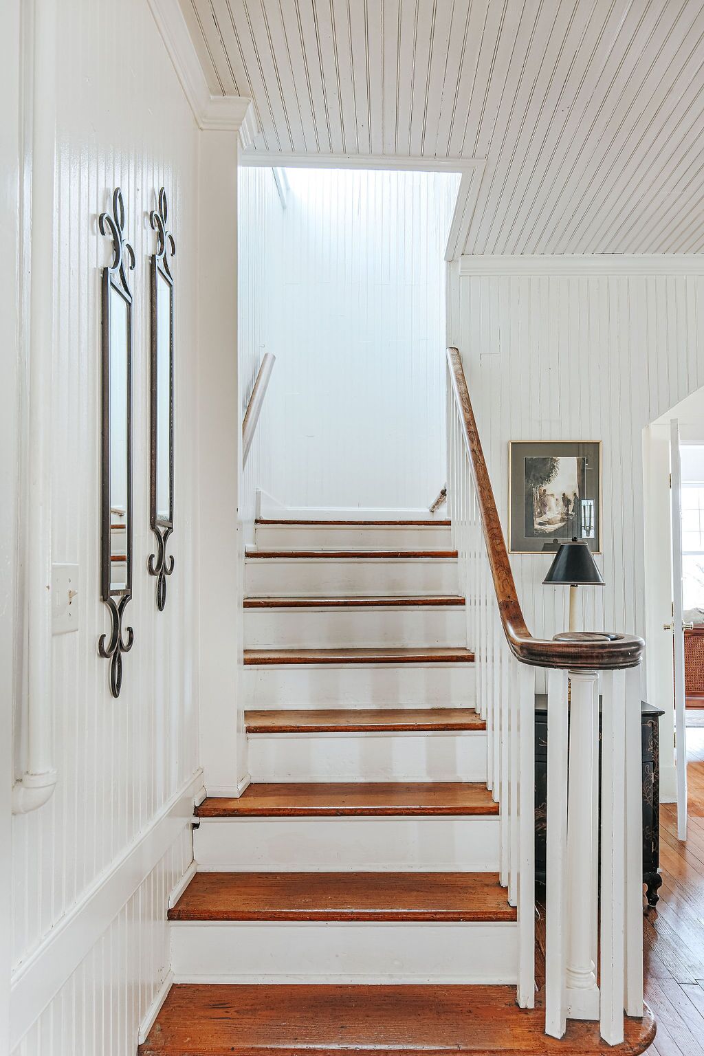 Un escalier aux murs blancs et aux marches en bois menant à un palier.