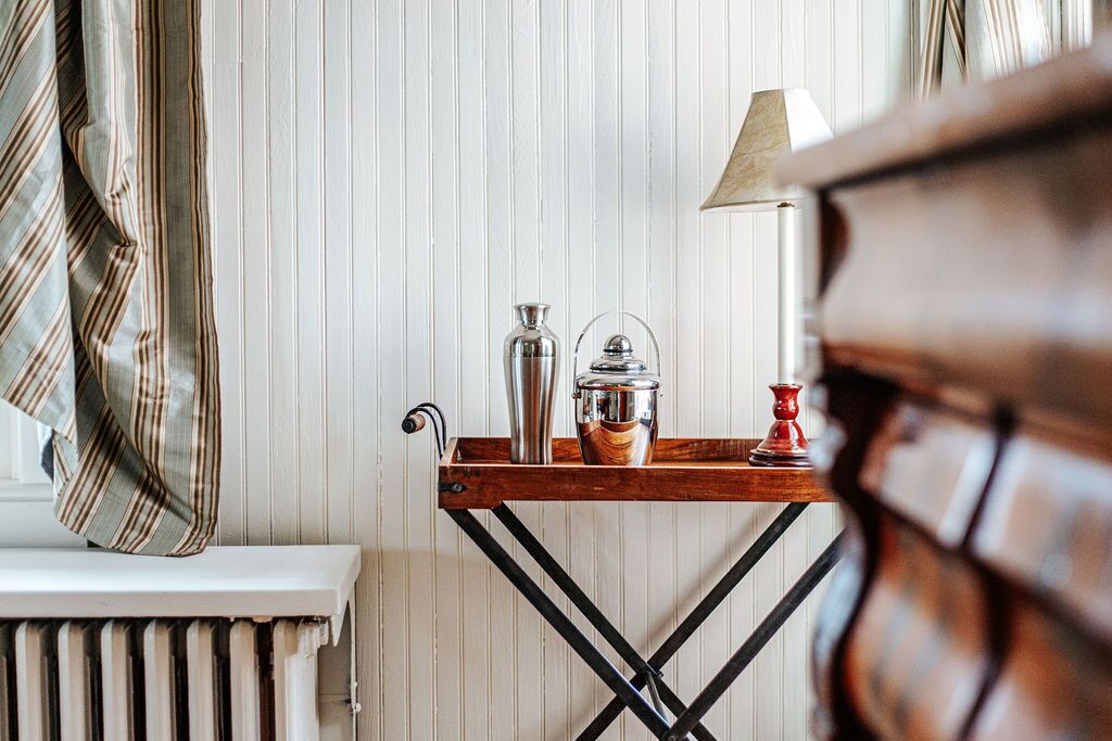 A wooden table with a metal pitcher, a glass container, and a red candle holder.