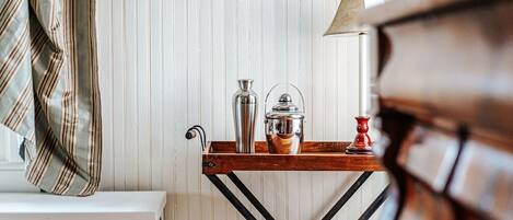 A wooden table with a metal pitcher, a glass container, and a red candle holder.