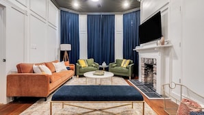 A living room with a sofa, two armchairs, a coffee table, a fireplace, and a TV. - Historic Savannah Nest with Private Parking & Pet friendly (Savannah)