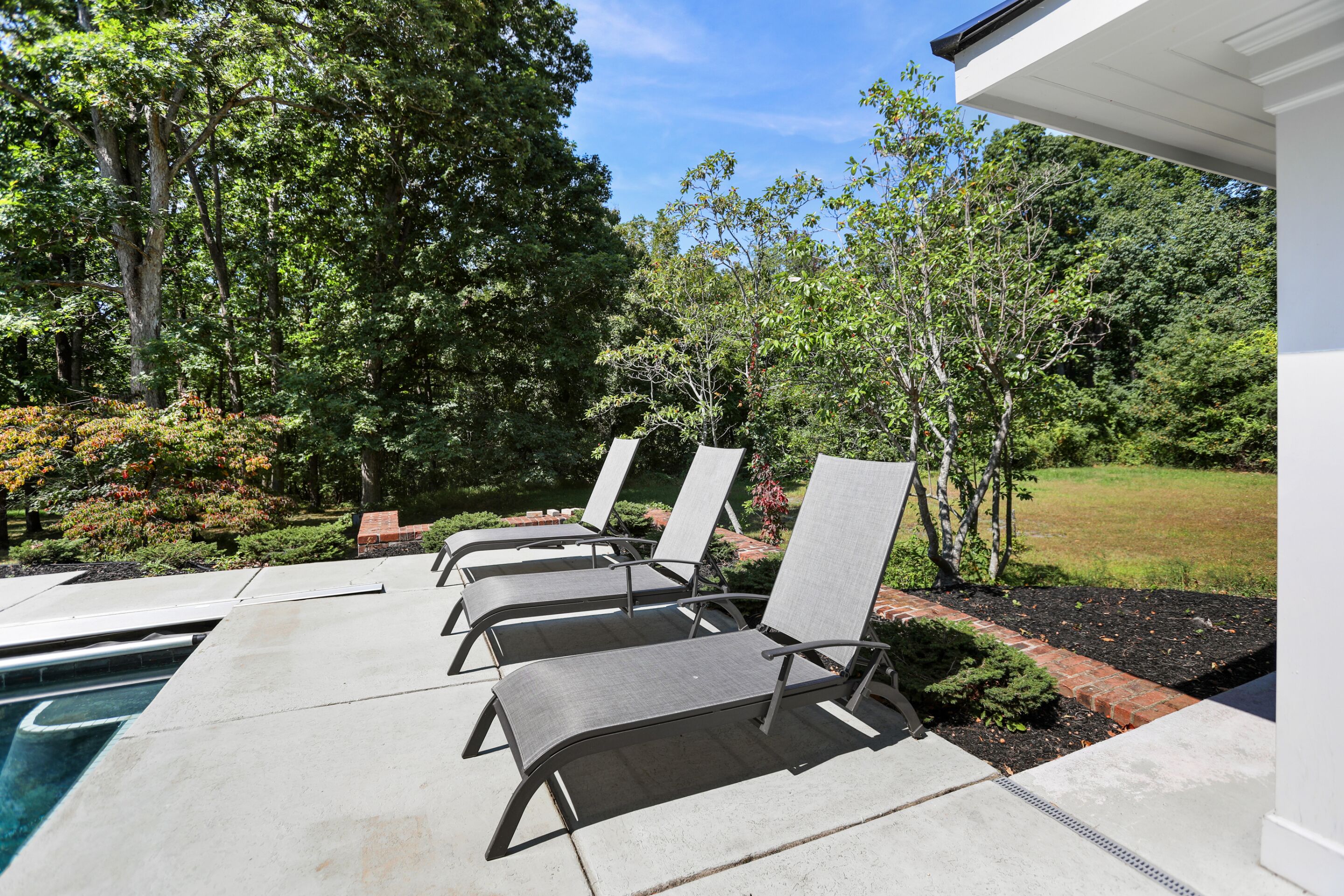 A poolside area with lounge chairs and a clear view of the surrounding garden.