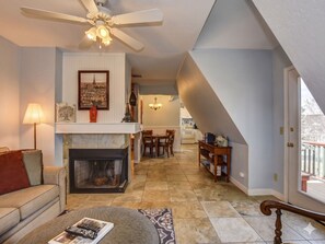 Ein Wohnzimmer mit Kamin, Deckenventilator und Essbereich mit Tisch und Stühlen.