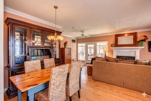 Ein Essbereich mit Holztisch und Korbstühlen, einem Kamin und einem Sofa in einem Wohnzimmer.
