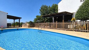 A swimming pool with a wooden deck, a covered seating area, and a fenced patio. - Casa rural de gran capacidad (Alcala la Real)