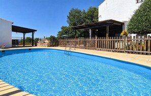 Ein Pool mit Holzterrasse, einer überdachten Lounge und einer umzäunten Terrasse.