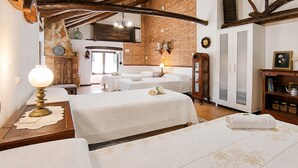 A hotel room with two beds, a wooden table with a lamp, a brick wall, and a wardrobe. - Casa rural de gran capacidad (Alcala la Real)