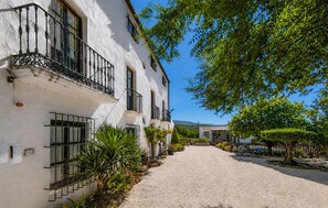 A white building with balconies, a gravel path, and greenery. - Casa rural de gran capacidad (Alcala la Real)