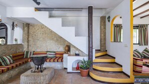 Una sala de estar con pared de piedra, un conjunto de sofá, una mesa de centro y una escalera con escalones amarillos.