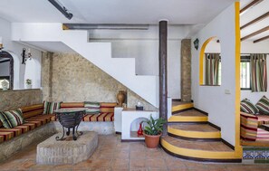 Ein Wohnzimmer mit Steinwand, einer Sofagarnitur, einem Couchtisch und einer Treppe mit gelben Stufen.