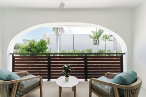 A balcony with wicker furniture, a small table, and a potted plant. - Casa Coral - Boca Poolside Escape (Boca Raton)