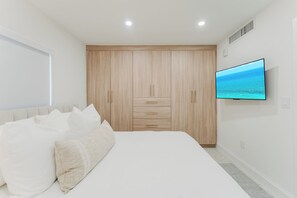 A bedroom with a bed, a TV, and a wardrobe. - Casa Coral - Boca Poolside Escape (Boca Raton)