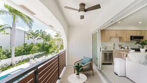 A balcony with a pool, a ceiling fan, a dining area with a table and chairs, and a kitchen area with cabinets and appliances.