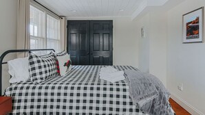 Une chambre avec une couvre-lit à carreaux, une porte noire et un tableau encadré accroché au mur.