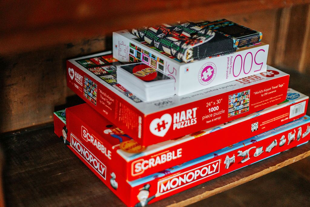 Una pila de juegos de mesa, incluyendo Scrabble, Monopoly y puzles Hart.