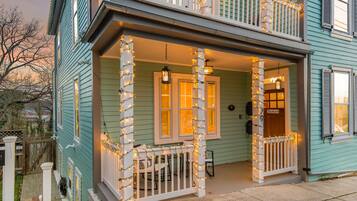 A two-story house with a porch decorated with string lights, a wooden fence, and a sign that reads 'Zondervan.'
