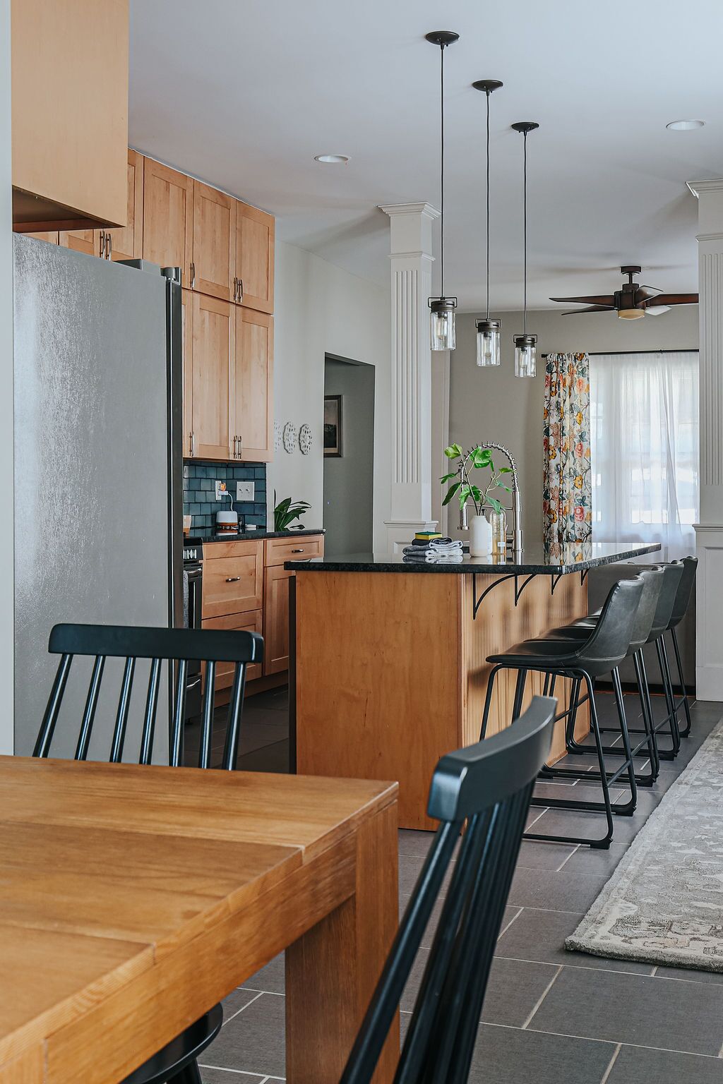 A modern kitchen with wooden cabinets, a central island, and pendant lighting.