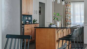 A modern kitchen with wooden cabinets, a central island, and pendant lighting.