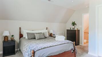 A bedroom with a bed, nightstands, a dresser, and a plant.