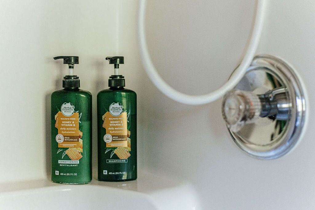 Deux flacons verts de shampoing et d’après-shampoing Herbal Essences dans un lavabo de salle de bain.