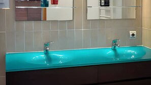 Ein Badezimmer mit einem langen, türkisblauen Waschbecken und einem Spiegel darüber.