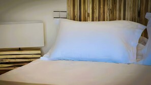 Ein ordentlich bezogenes Bett mit weißem Kopfkissen und weißer Daunendecke, ein Holz-Kopfteil und eine Holzpaneelausstattung.