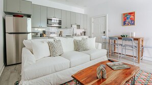 A modern kitchen with grey cabinets, a stainless steel refrigerator, and a microwave. - The Social Loft (Staunton)