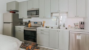 A compact kitchen with a microwave, oven, sink, and a coffee maker. - The Social Loft (Staunton)