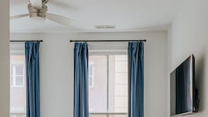 A bedroom with a bed, a desk, a chair, a television, and a window with curtains. - The Social Loft (Staunton)