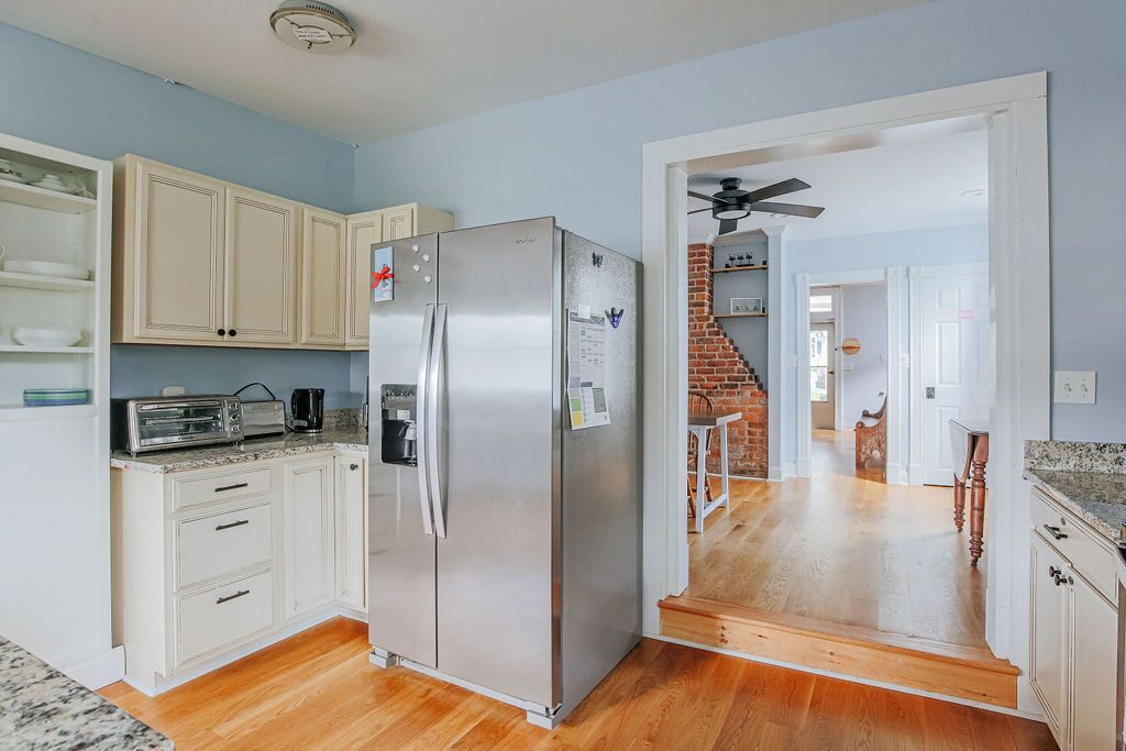 A modern kitchen with white cabinetry, a stainless steel refrigerator, a built-in oven, and a microwave.