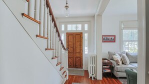 Eine Treppe mit weißen Geländern und Holzhandläufen, die zu einer Holztür führt.