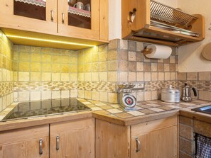 A kitchen with wooden cabinets, a tiled backsplash, a scale, a coffee pot, and a dish rack. - Chalet Ralon by Interhome (Bormio)
