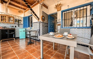 Eine Küche mit einer blauen Tür, einem weißen Tisch mit Speisen und einem blauen Kühlschrank.
