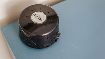 A black object with a circular top and a label reading "dhm" on a blue surface.