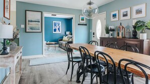 A dining area with a wooden table and chairs, a hanging light fixture, and artwork on the walls. - Tucked Inn: Upper Unit (Nellysford)