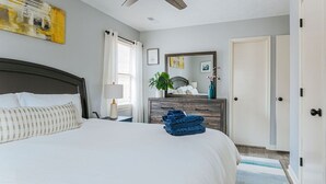 A neatly arranged bedroom with a bed, a dresser, a mirror, and a ceiling fan. - Tucked Inn: Upper Unit (Nellysford)