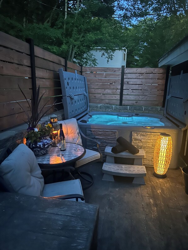 Une terrasse extérieure dotée d’un jacuzzi, d’un espace salon et d’une lampe décorative.
