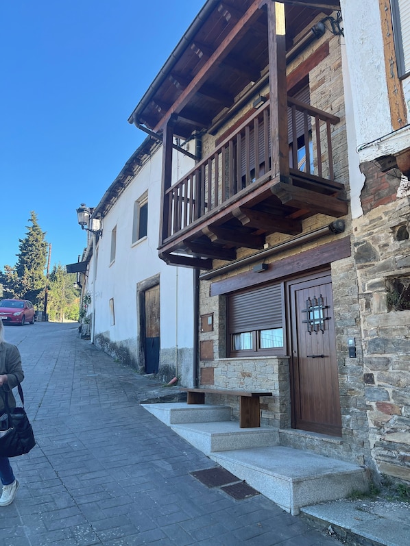 A traditional building with a stone facade, wooden balcony, and a closed wooden door.