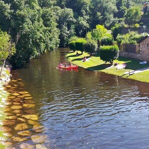 A river with a red boat, grassy banks, and trees.