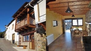 Un edificio con balcón de madera, fachada de piedra y un comedor con mesa y sillas.