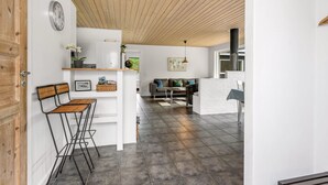 Et moderne interiør med træloft, et køkken og en siddekrog med sofa og stole.