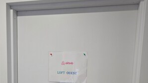 Valkoinen ovi, jossa on kyltti, josta ilmenee, että kyseessä on Airbnb-majoitus nimeltä »LOFT OUEST».