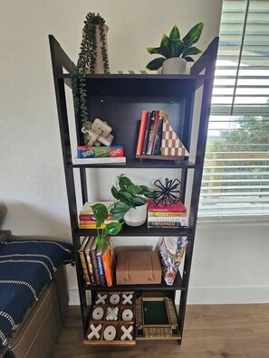 Ein Bücherregal mit Büchern, Gesellschaftsspielen und Pflanzen.