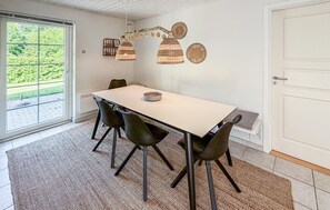 A dining area with a white table, four chairs, a woven light fixture, and a view through a glass door. - Pet friendly home in Gråsten with sauna (Gråsten)